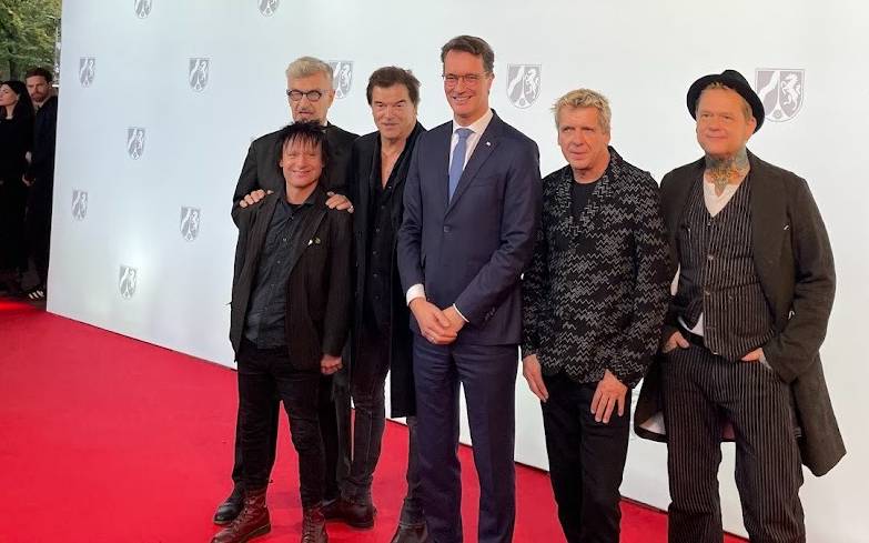 Die Toten Hosen und NRW-Ministerpräsident Hendrik Wüst auf dem rote Teppich. Die Toten Hosen bekommen den NRW-Staatspreis für ihr kulturelles Lebenswerk und für ihre sozialen Einsatz.
