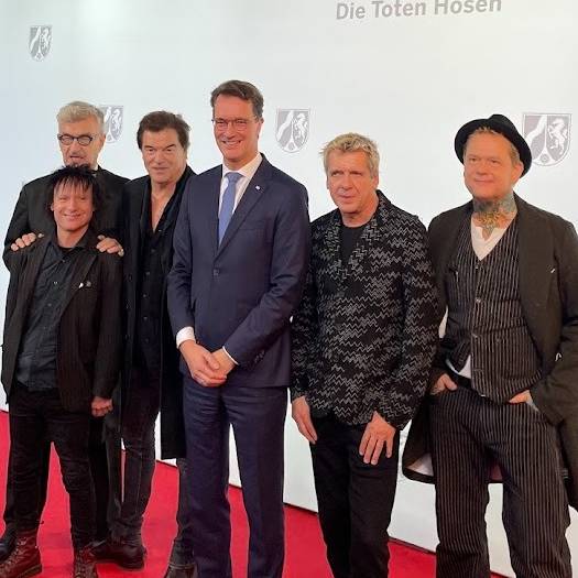 Die Toten Hosen und NRW-Ministerpräsident Hendrik Wüst auf dem rote Teppich. Die Toten Hosen bekommen den NRW-Staatspreis für ihr kulturelles Lebenswerk und für ihre sozialen Einsatz.