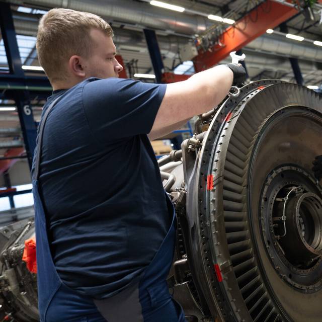 Mitarbeiter arbeiten bei MTU Maintenance Berlin-Brandenburg an einem Antrieb,