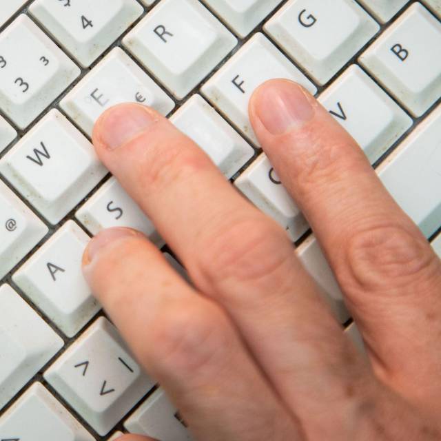 Mann tippt auf einer Tastatur
