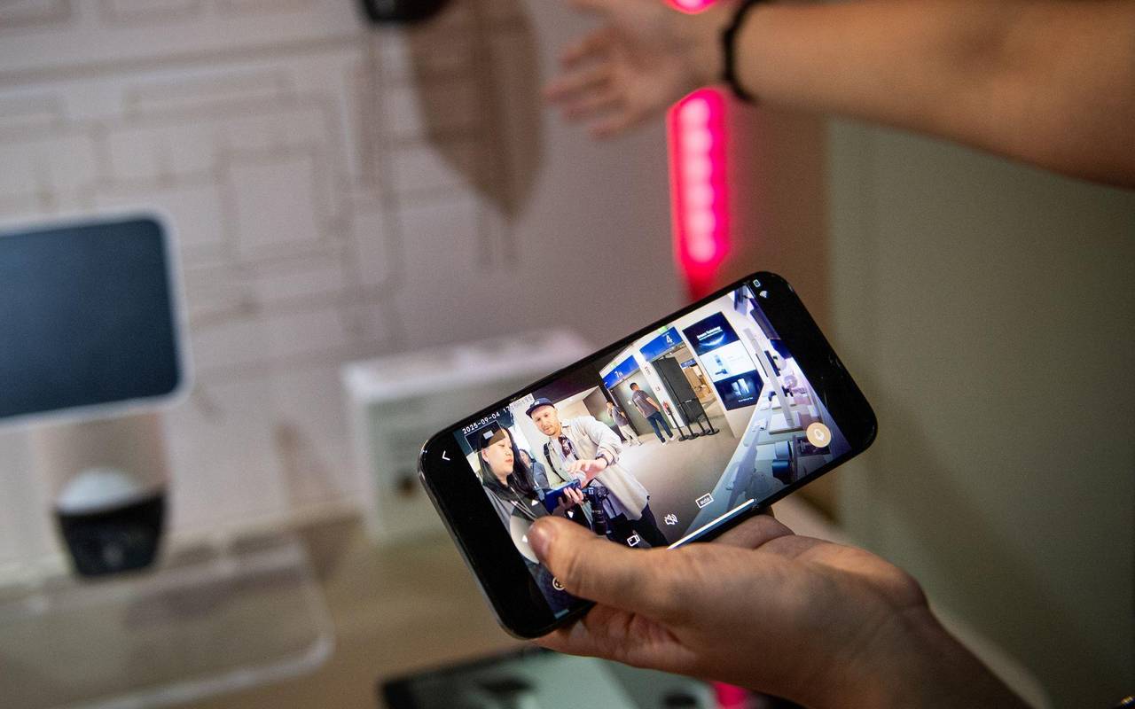 Eine Frau steuert mit einem Smartphone eine Ueberwachungskamera