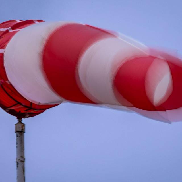 Windsack weht bei Regen und kräftigem Wind am Mast