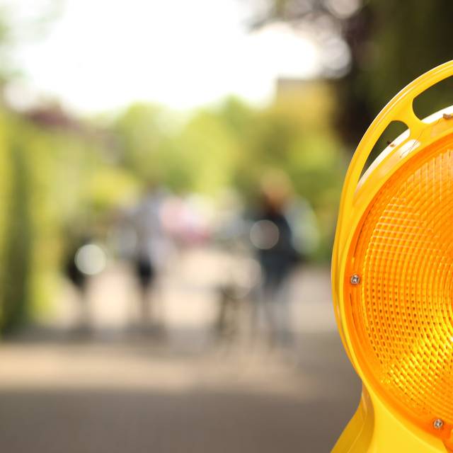 Eine Nahaufnahme einer gelb blinkenden Warnleuchte im Straßenverkehr, die zum Beispiel bei Sperrungen verwendet wird.