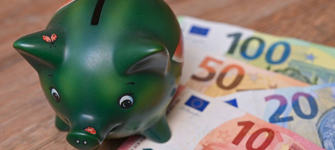 Eine Spardose mit Geldscheinen liegt auf einem Tisch