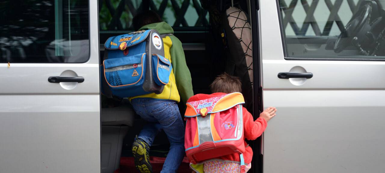 Vor einer Schule steigen Kinder ein privates Fahrzeug