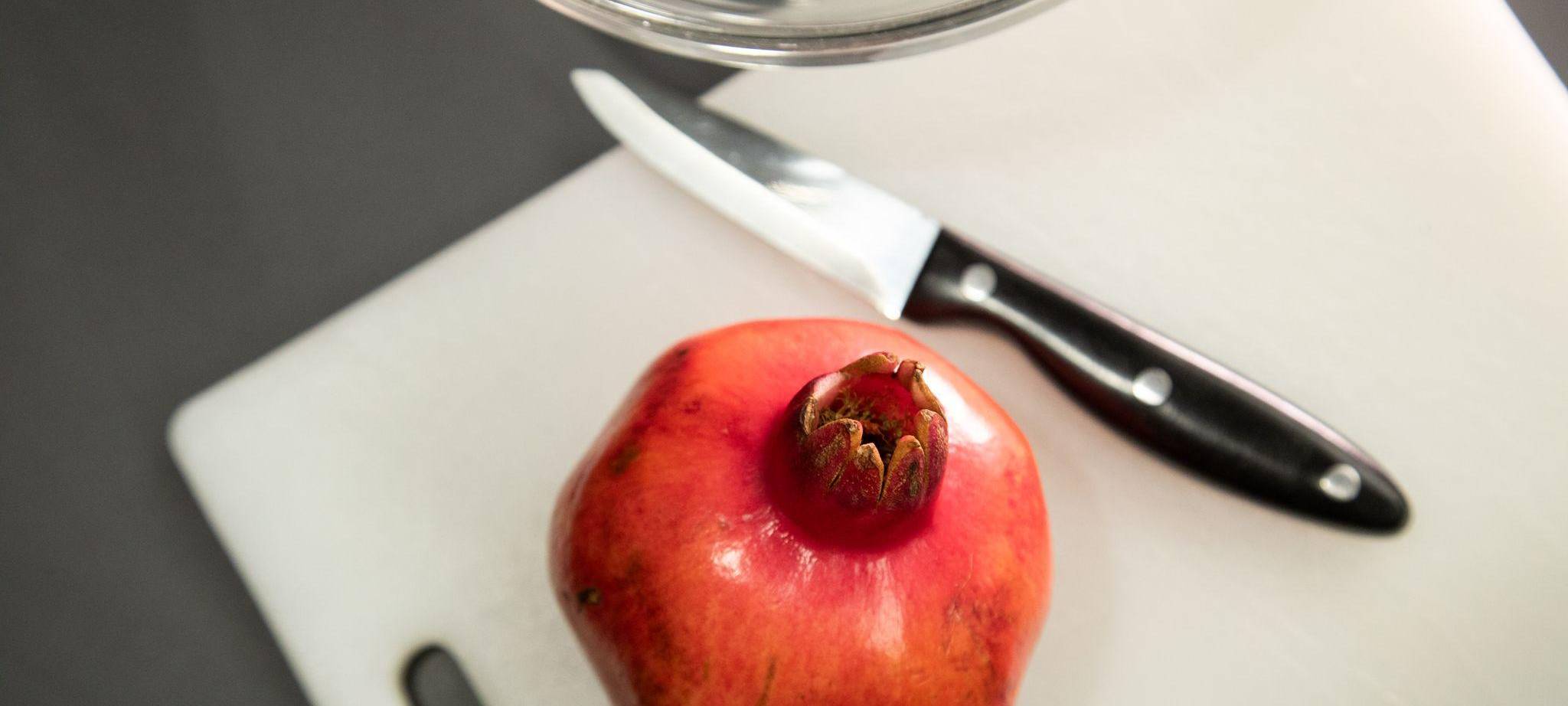Granatapfel liegt neben einem Messer auf einem Tisch