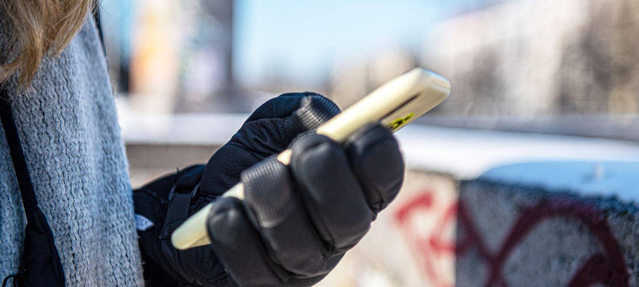 Eine warm angezogene Frau hält bei Kälte ein Handy