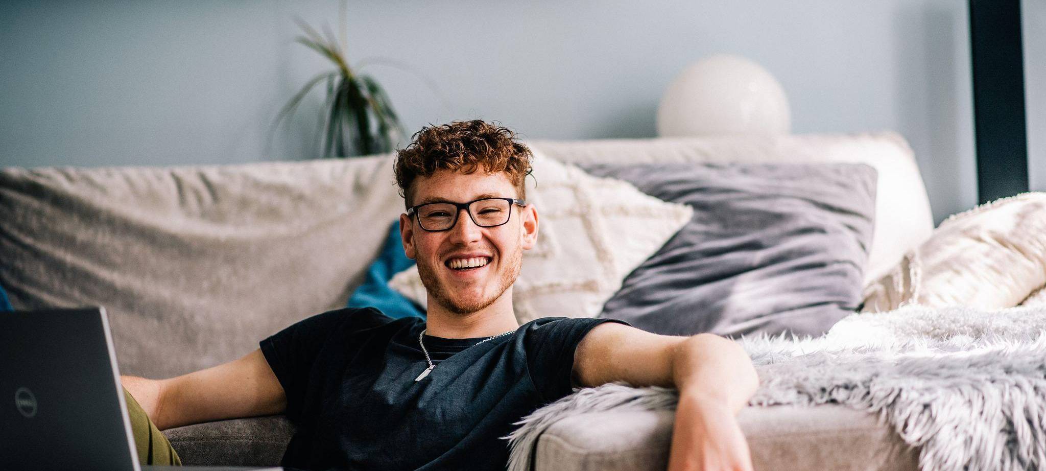 Ein Jugendlicher sitzt im Wohnzimmer vor einem Laptop