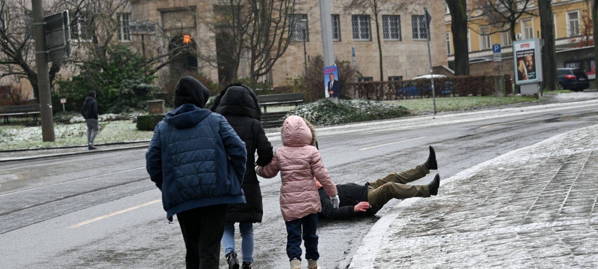 Ein Mann stürzt bei Eisglätte vom Gehweg auf die Straße