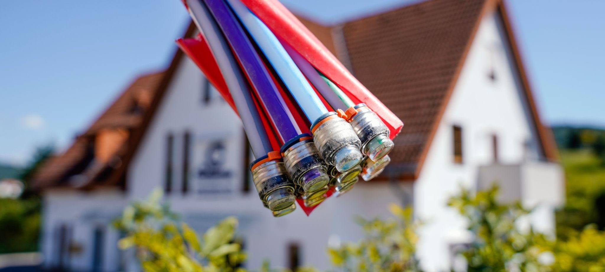 Bündel mit Umhüllungen für Glasfaserkabel vor einem Wohnhaus