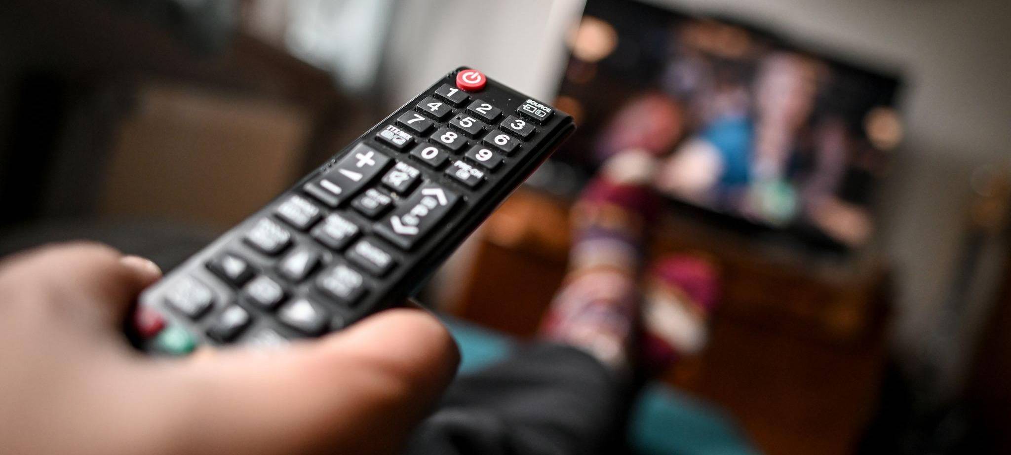 Mann sitzt mit einer Fernbedienung vor dem Fernseher