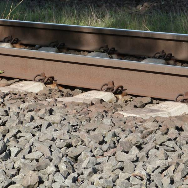 Gleisbett/Schiene mit Wiese im Hintergrund, schattig beleuchtet